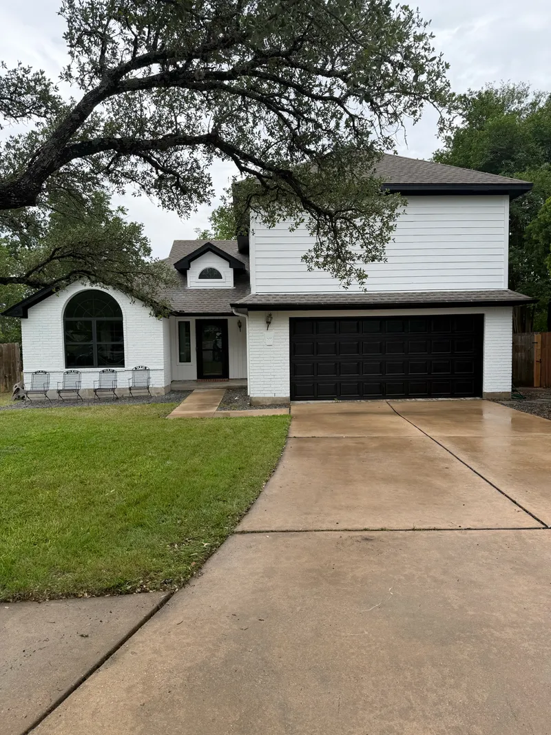 Two story Austin home repainted bright white with black garage door by V&S Painting
